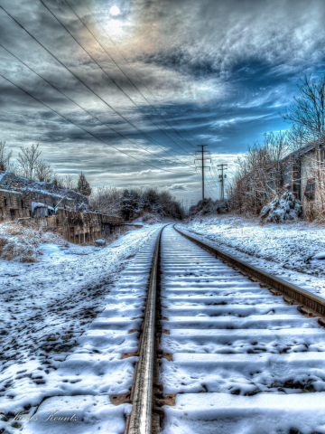 Railroad tracks stretching to infinity on a turbulent snowy winter day